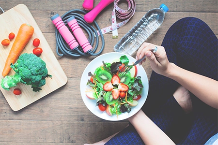 uma mulher realizando uma alimentação saudável, sentada no chão