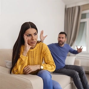 casal discutindo, sentado no sofá