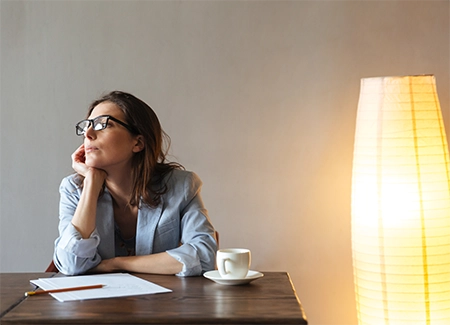 mulher com a mão no queixo, pensativa