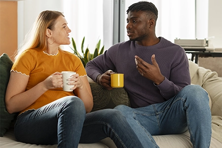casal conversando e tomando café, sentados no sofá